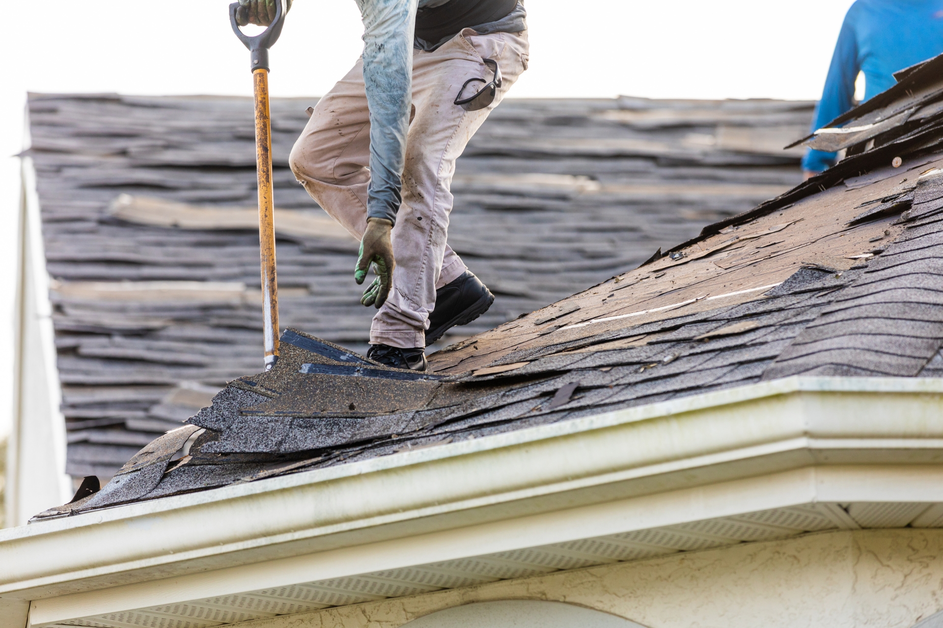 Roof tear-off process showing old shingles being removed from a residential roof